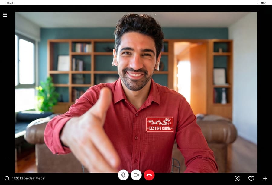 Hombre de sonrisa amable, vestido con camisa roja da la mano para saludar.