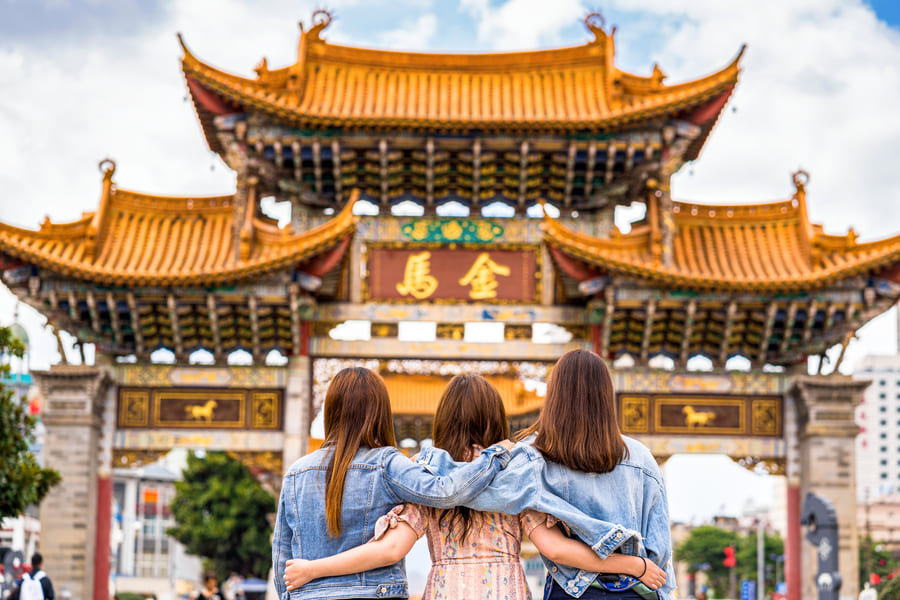 fotografía de tres mujeres abrazandose frente a un templo chino